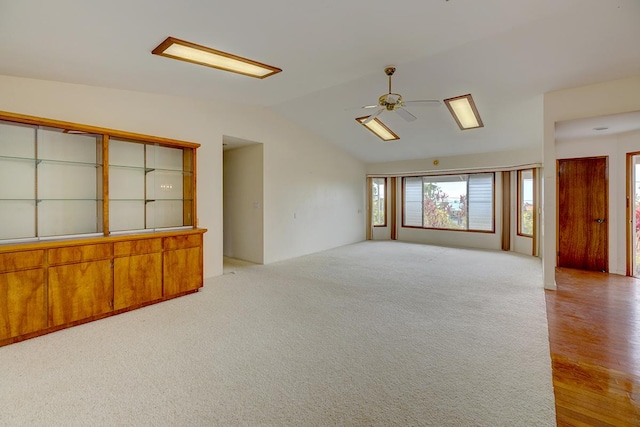 unfurnished room with vaulted ceiling, a ceiling fan, and light colored carpet