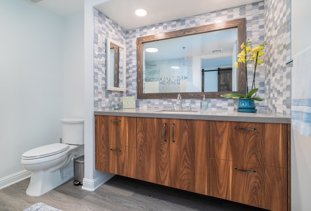 bathroom with hardwood / wood-style floors, vanity, toilet, and tasteful backsplash