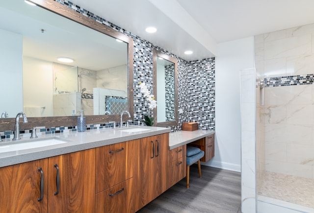 bathroom with hardwood / wood-style floors, vanity, a tile shower, and decorative backsplash