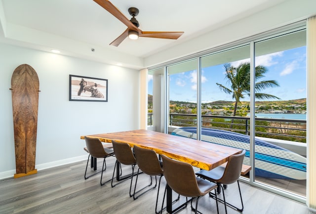 dining space featuring ceiling fan, a water view, and wood-type flooring