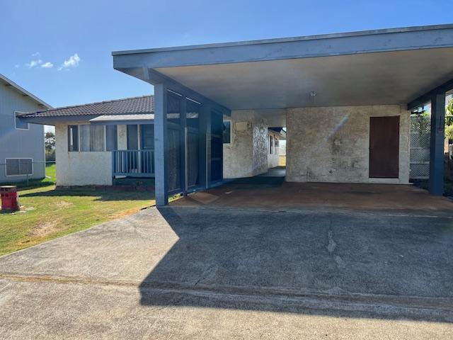 exterior space with a carport and a lawn