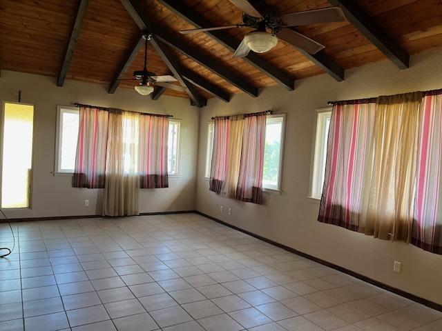 tiled empty room featuring ceiling fan, lofted ceiling with beams, and wooden ceiling