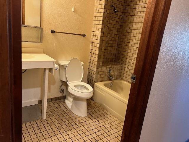 bathroom featuring tile patterned floors, toilet, and tiled shower / bath