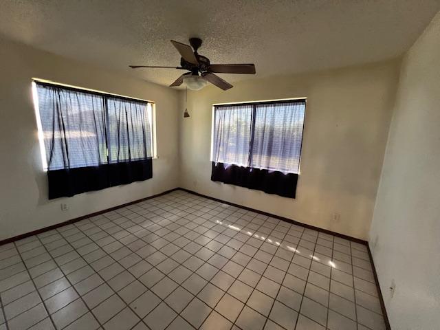 tiled spare room with ceiling fan and a textured ceiling