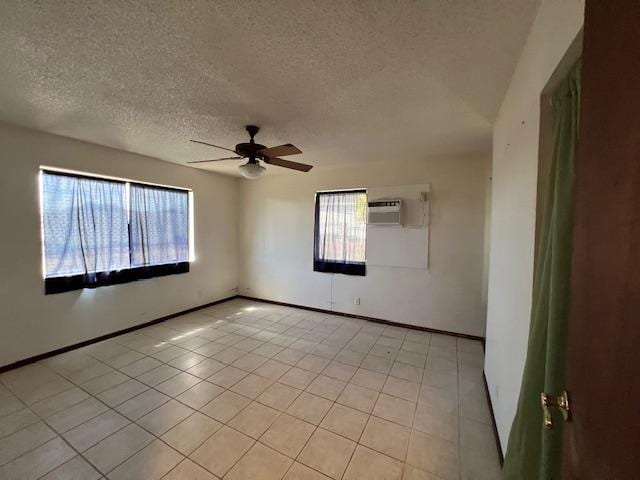 tiled empty room featuring a textured ceiling, a wall mounted AC, and ceiling fan