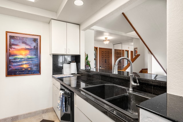 kitchen featuring sink, stainless steel dishwasher, backsplash, dark stone counters, and white cabinets