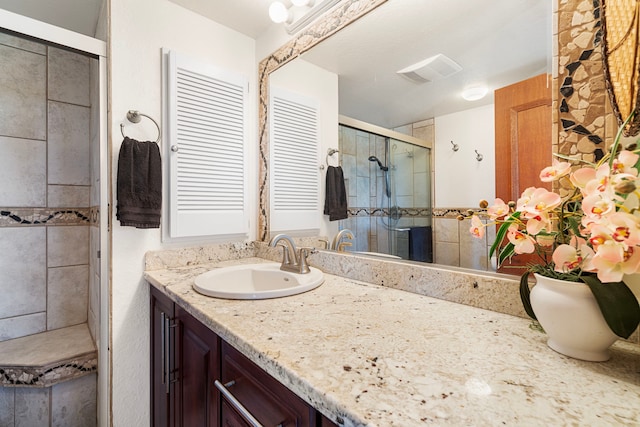 bathroom featuring a shower with door and vanity