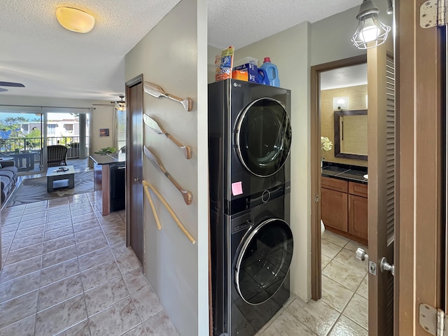 laundry area with ceiling fan, light tile patterned flooring, a textured ceiling, and stacked washer and clothes dryer