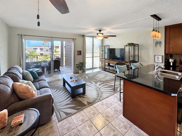 tiled living room featuring a textured ceiling, ceiling fan, and sink