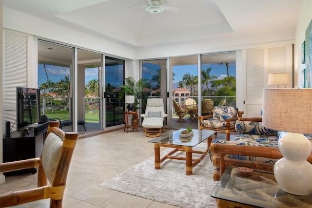 sunroom with ceiling fan, a wealth of natural light, and a raised ceiling