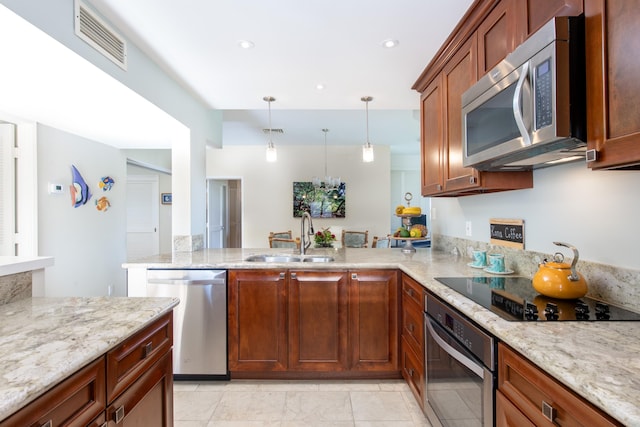 kitchen featuring appliances with stainless steel finishes, decorative light fixtures, sink, kitchen peninsula, and light stone counters