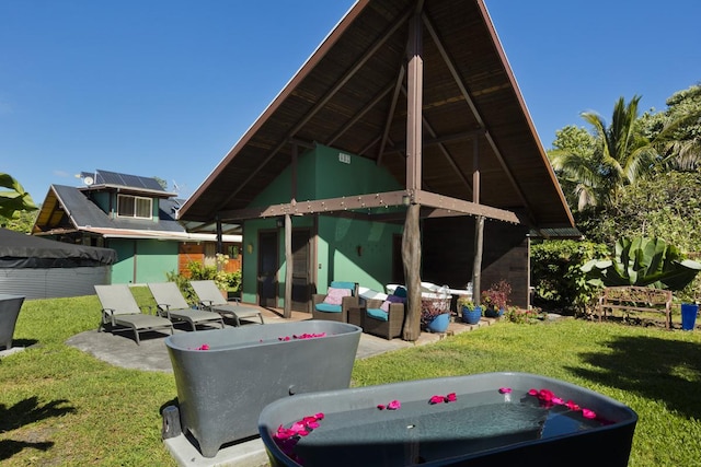 back of property with a lawn, an outbuilding, an outdoor hangout area, and a patio