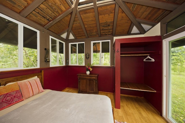 bedroom featuring lofted ceiling with beams, wood ceiling, light hardwood / wood-style flooring, and a closet