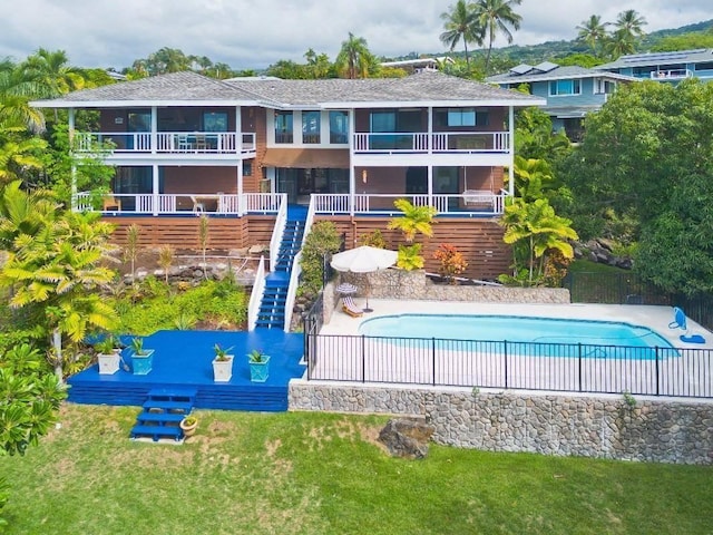 rear view of property featuring a lawn, a fenced in pool, and a patio