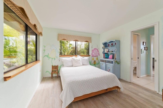 bedroom with light hardwood / wood-style floors and ensuite bath