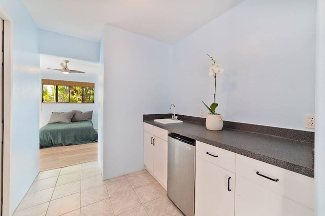 kitchen with ceiling fan, sink, light tile patterned floors, dishwasher, and white cabinets