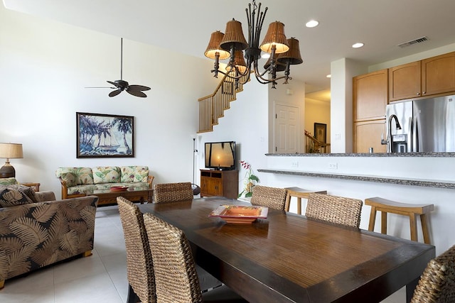 tiled dining space featuring ceiling fan with notable chandelier