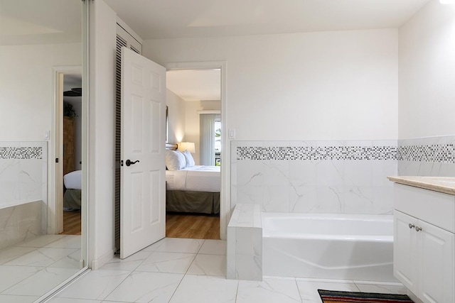 bathroom with vanity, tile walls, and a tub