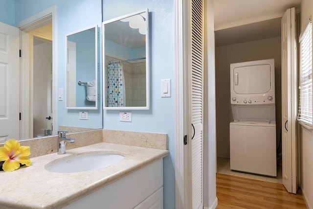 bathroom with hardwood / wood-style floors, vanity, curtained shower, and stacked washer / drying machine