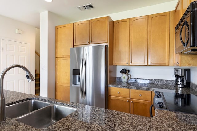 kitchen with stainless steel fridge with ice dispenser, range, dark stone counters, and sink