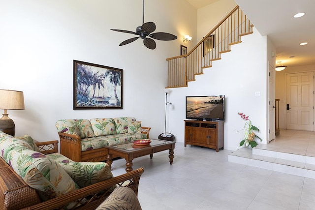 living room with ceiling fan, light tile patterned floors, and a high ceiling