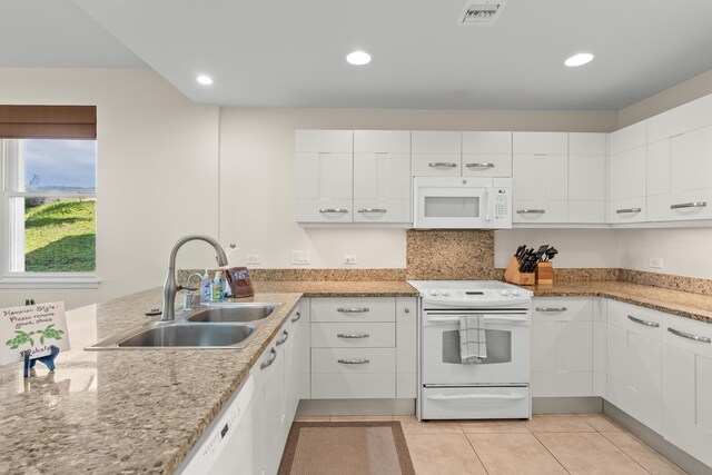 kitchen with white cabinets, white appliances, light stone counters, and sink