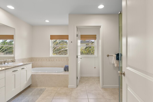 bathroom with tile patterned flooring, vanity, and tiled tub