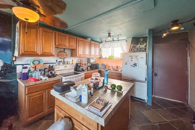 kitchen with tile counters, electric stove, sink, and stainless steel refrigerator