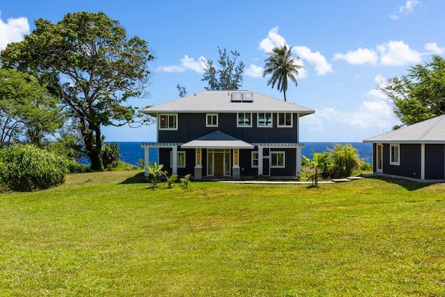 rear view of house with a yard and a water view