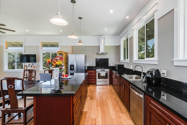 kitchen featuring wall chimney exhaust hood, plenty of natural light, sink, and appliances with stainless steel finishes