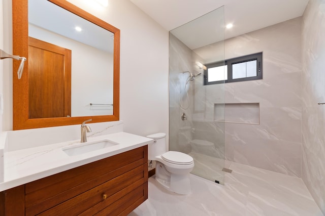 bathroom with toilet, vanity, and a tile shower