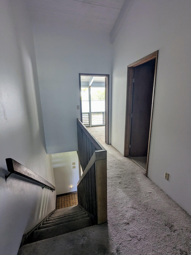 stairs with carpet floors and beamed ceiling