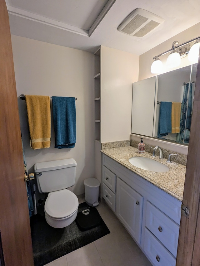 bathroom with toilet, vanity, and tile patterned flooring