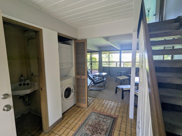 laundry room with stacked washer / drying machine, tile patterned flooring, and sink