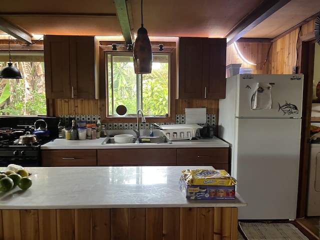 kitchen with black range with gas cooktop, sink, beam ceiling, decorative light fixtures, and white fridge