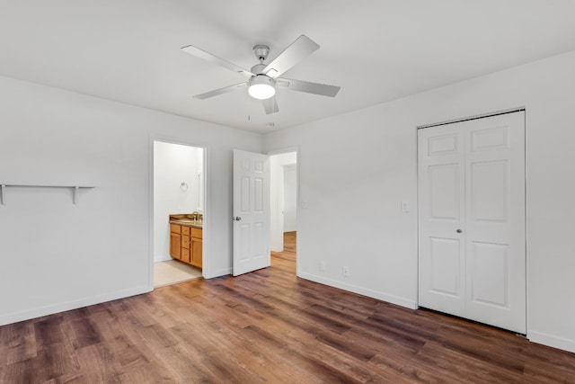 unfurnished bedroom featuring a closet, dark hardwood / wood-style floors, ceiling fan, and connected bathroom