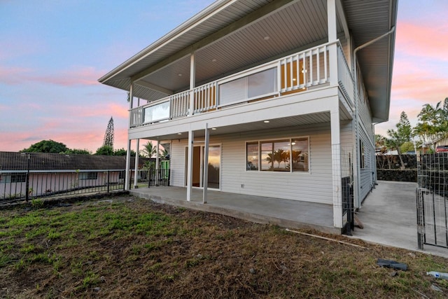 back house at dusk with a balcony and a patio area