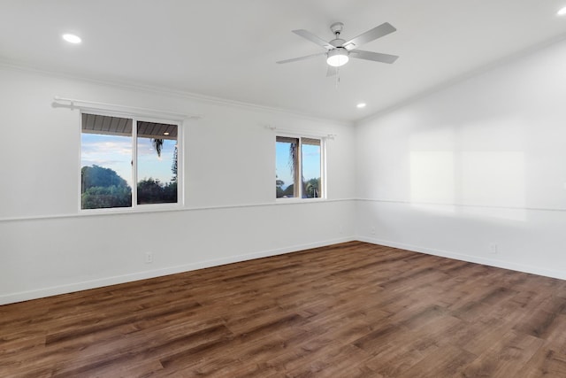 empty room featuring crown molding, dark wood-type flooring, ceiling fan, and a healthy amount of sunlight