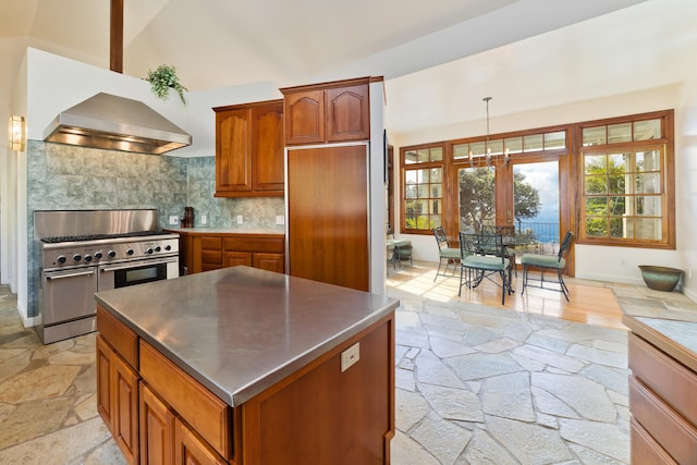 kitchen featuring tasteful backsplash, wall chimney range hood, pendant lighting, high end stainless steel range, and a kitchen island