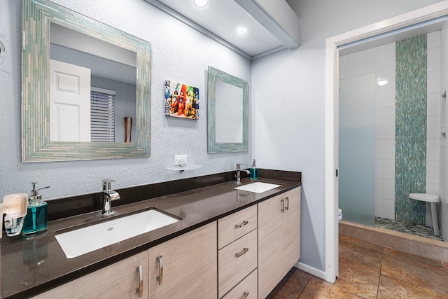 bathroom featuring a tile shower, vanity, and toilet