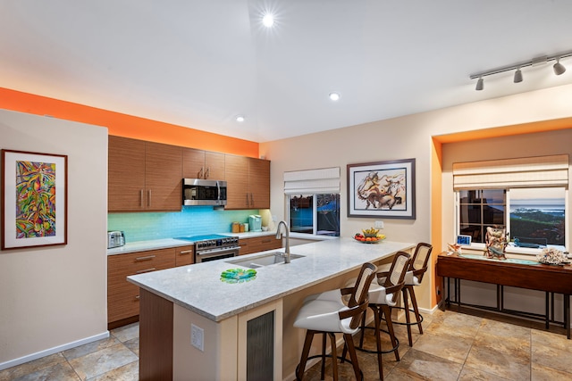 kitchen featuring light stone countertops, a kitchen breakfast bar, tasteful backsplash, stainless steel appliances, and sink