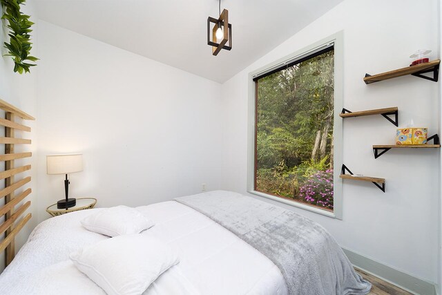 bedroom with hardwood / wood-style floors and lofted ceiling