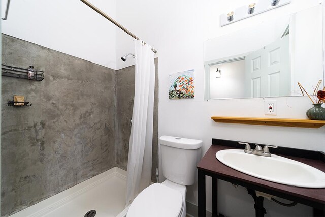 bathroom featuring sink, a shower with shower curtain, and toilet