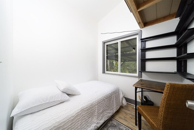 bedroom featuring beamed ceiling and hardwood / wood-style floors