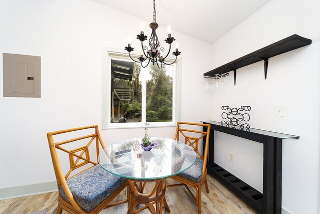 dining space with a notable chandelier, light hardwood / wood-style floors, and electric panel