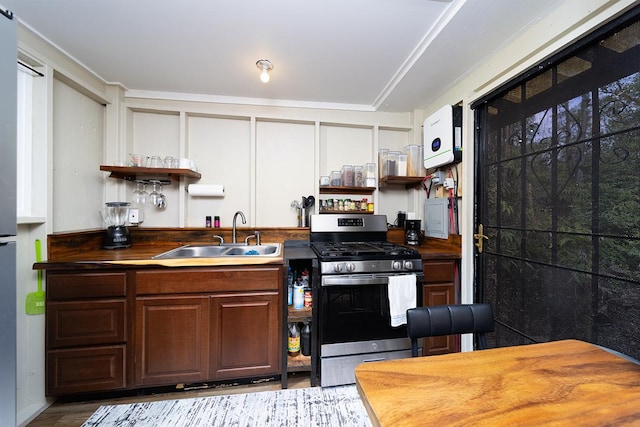 kitchen featuring stainless steel gas stove, light hardwood / wood-style floors, dark brown cabinets, and sink