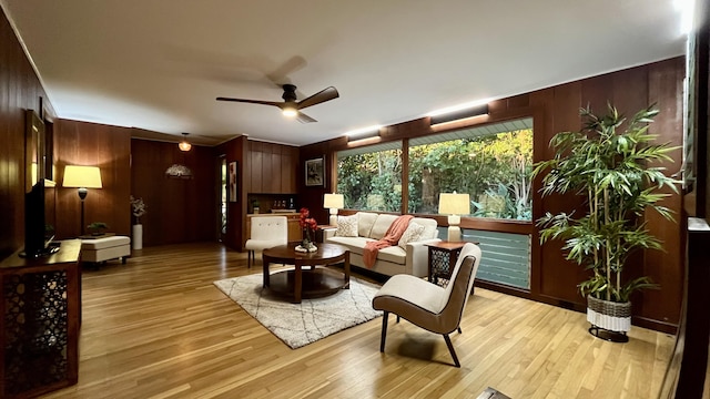 living room with wood walls, ceiling fan, and light hardwood / wood-style floors