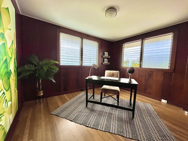 office area with light wood-type flooring and wood walls