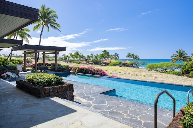 outdoor pool with a water view and a patio