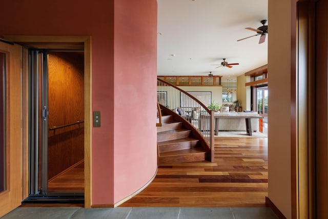 foyer featuring elevator, baseboards, stairway, and wood finished floors